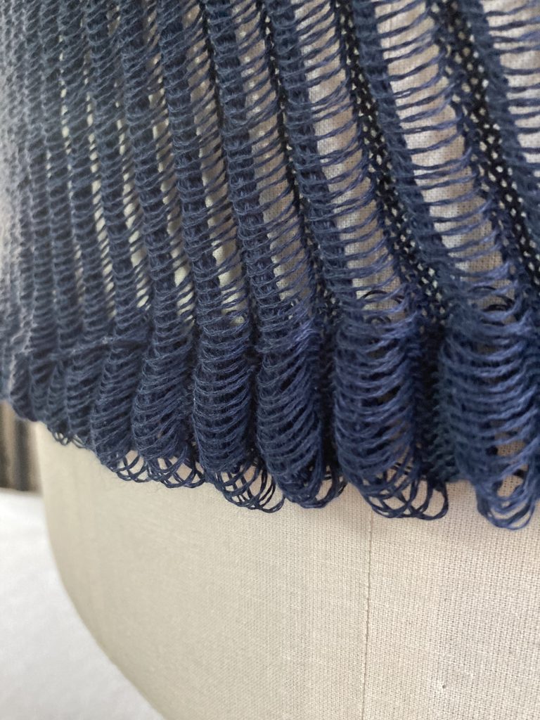 Close up of the hem edge of a ladder lace fabric in navy cotton